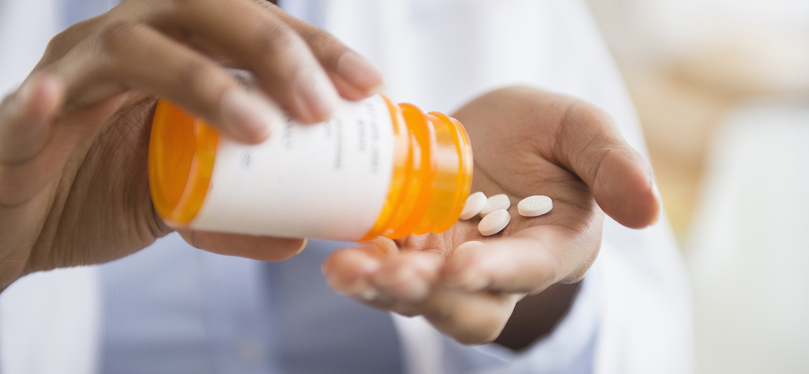 person pouring pills from pill bottle