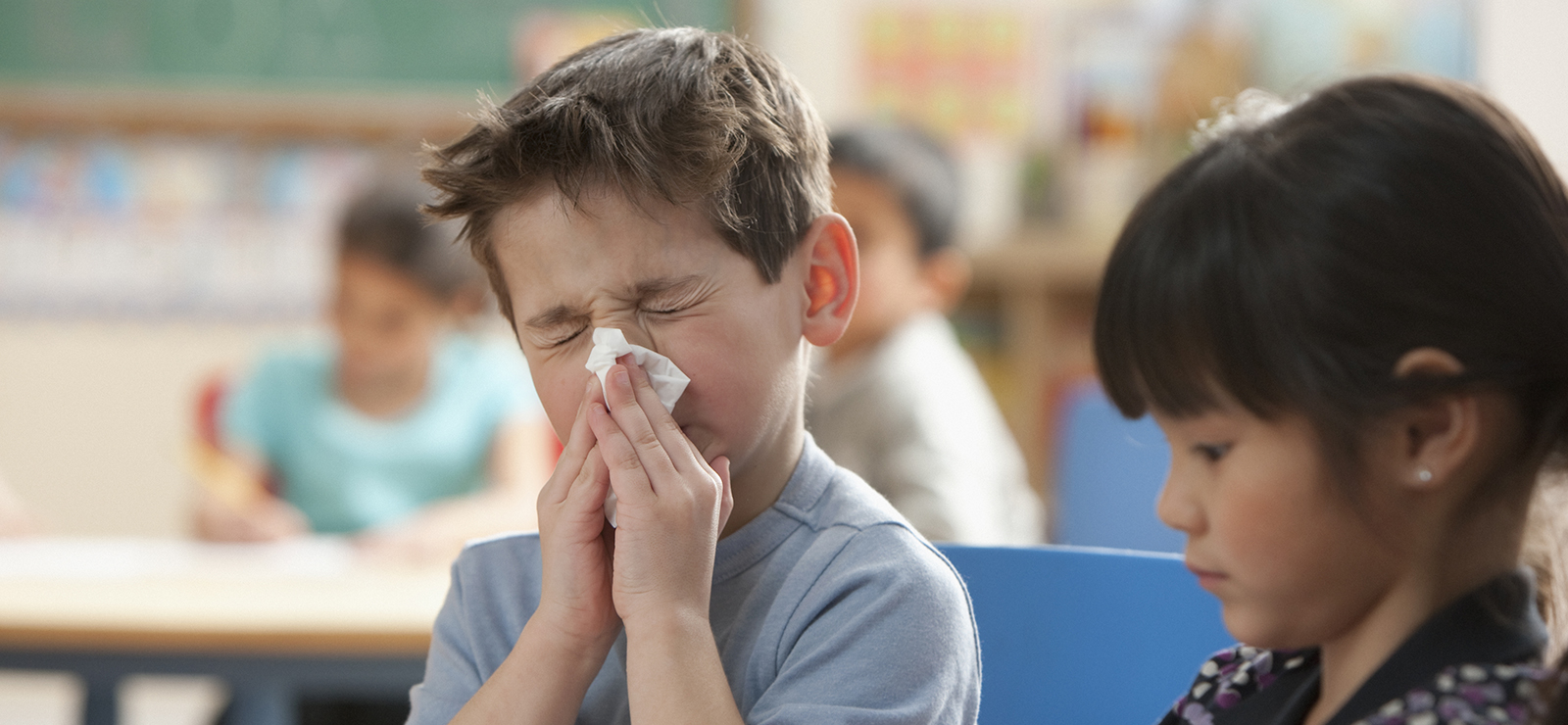 young boy blowing his nose