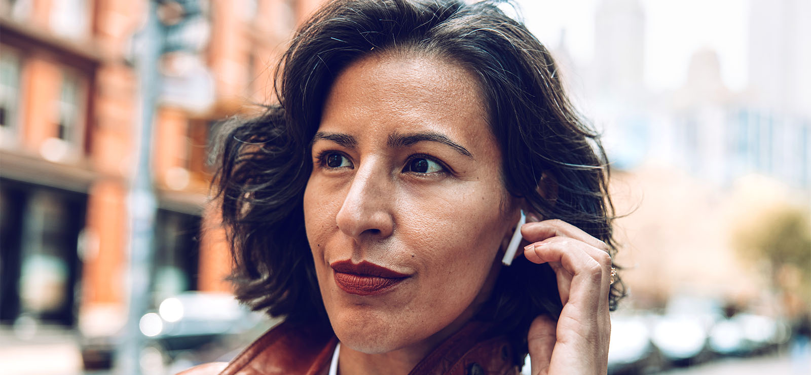 A woman outdoors wearing earbuds.