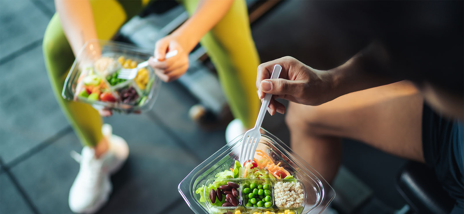 Two athletes sitting down eating a meal.