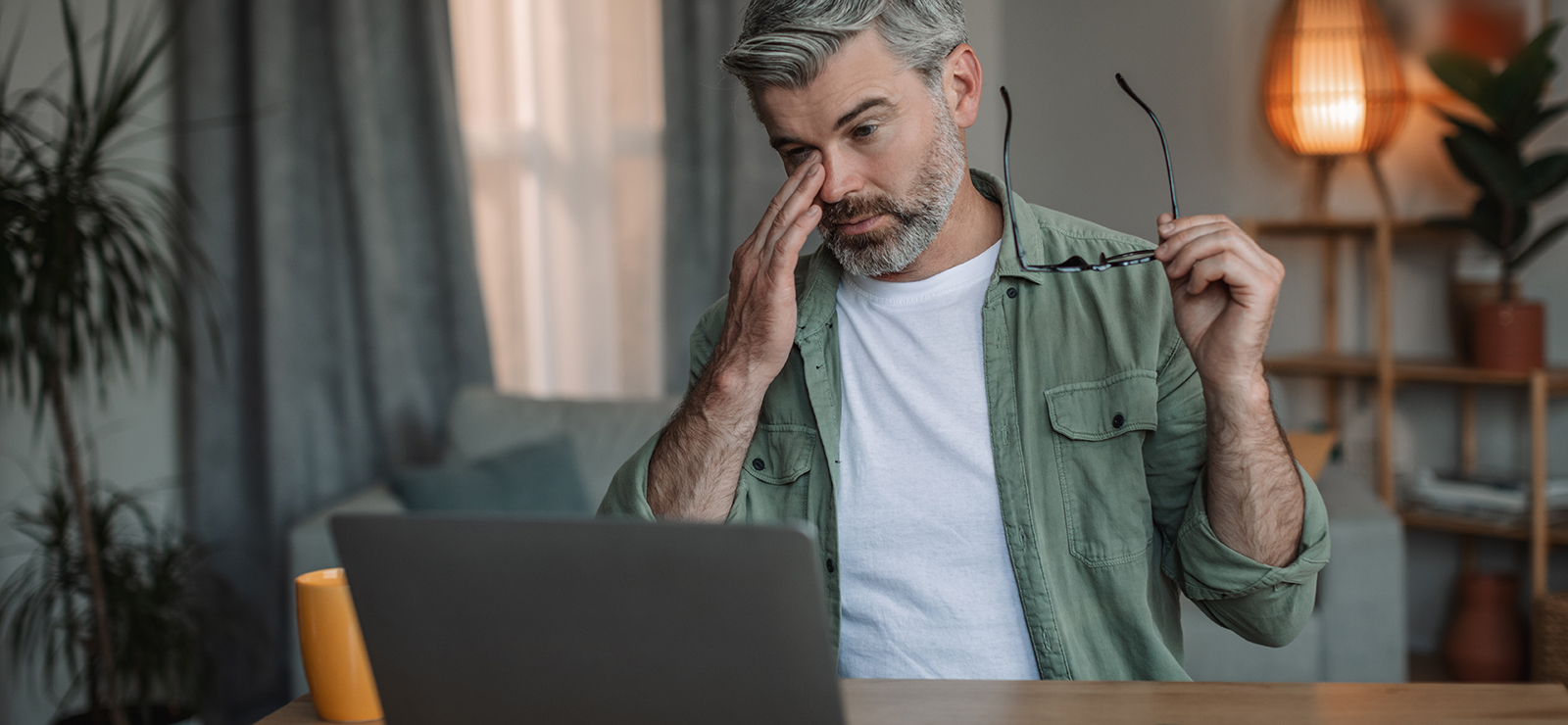 A man rubs his eyes after removing his glasses.
