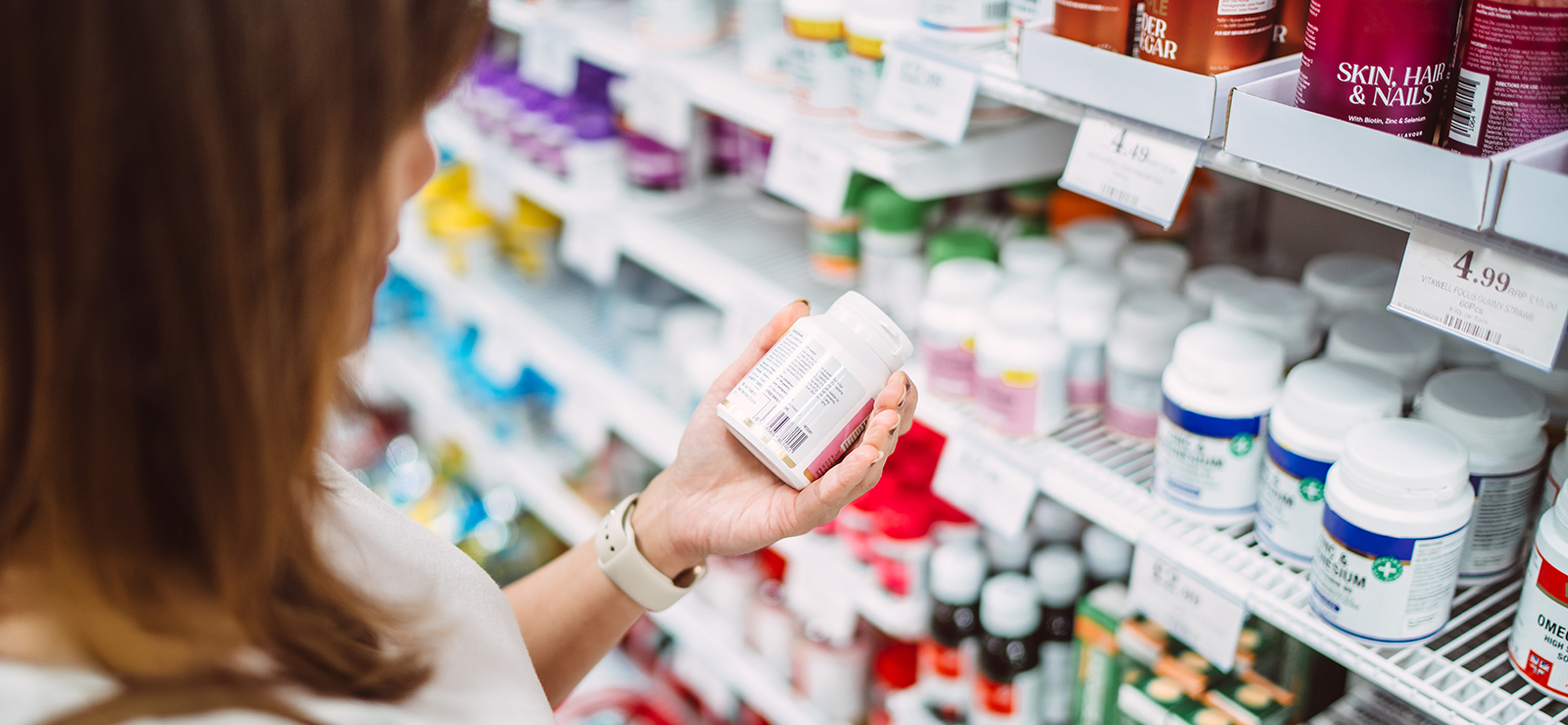 A woman is examining the label of some supplements.