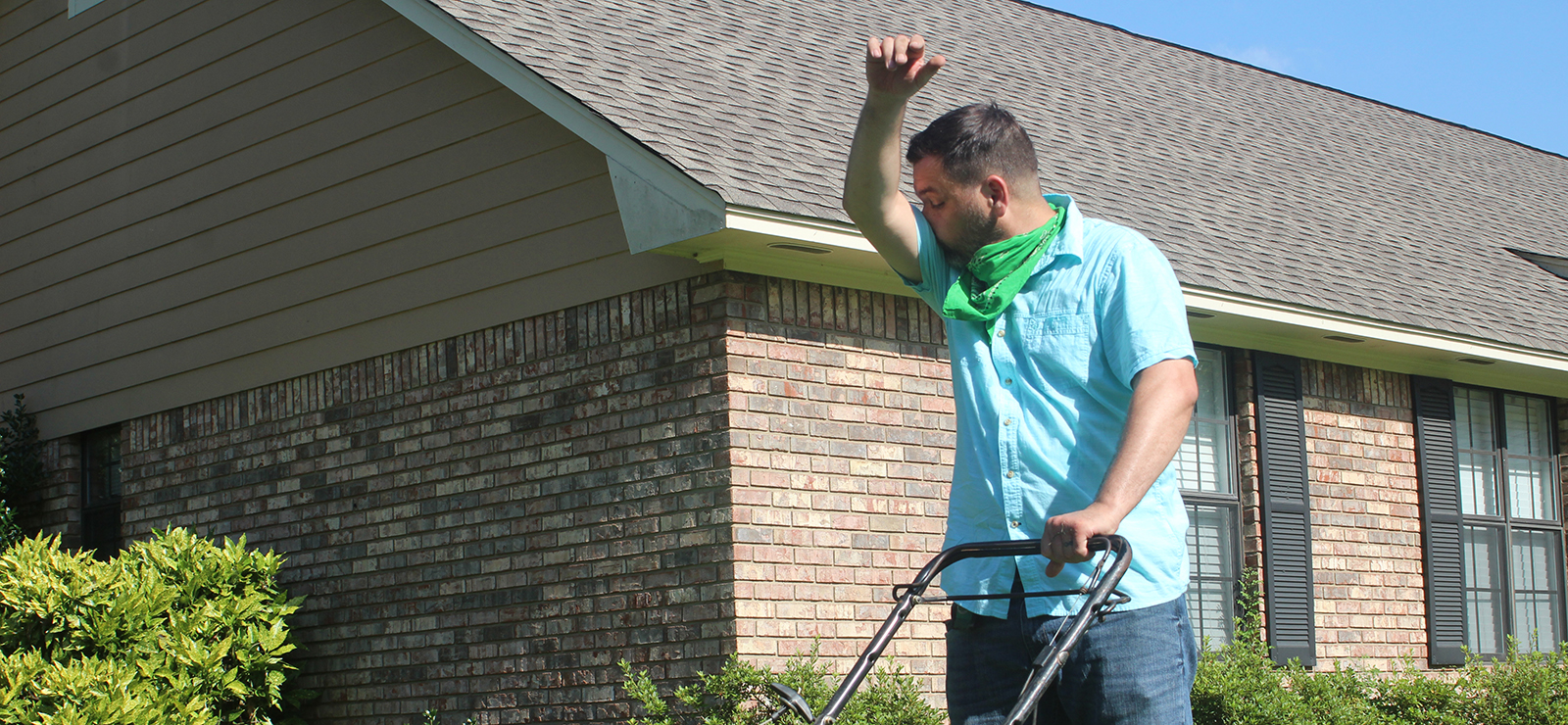 A man sneezing while mowing the lawn.