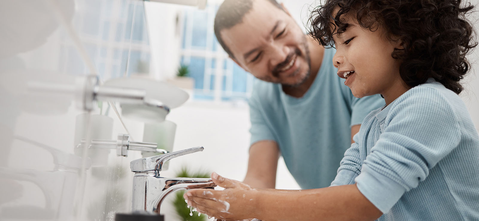 A father teaching his son how to wash his hands.