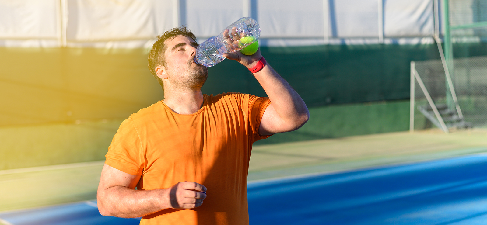 A man drinking a beverage after exercising outdoors.