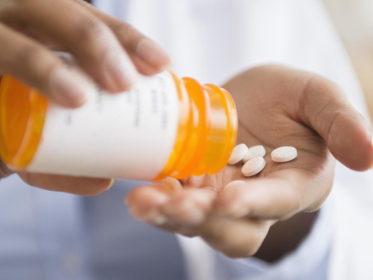 person pouring pills from pill bottle