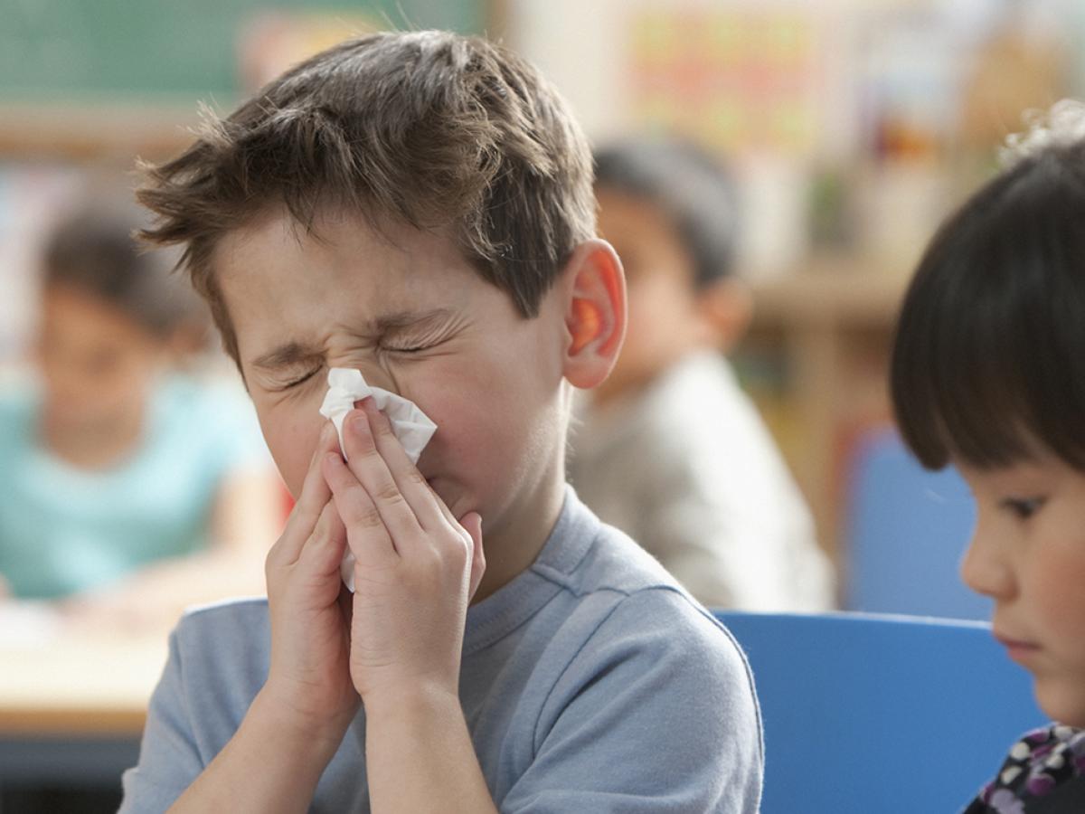 young boy blowing his nose