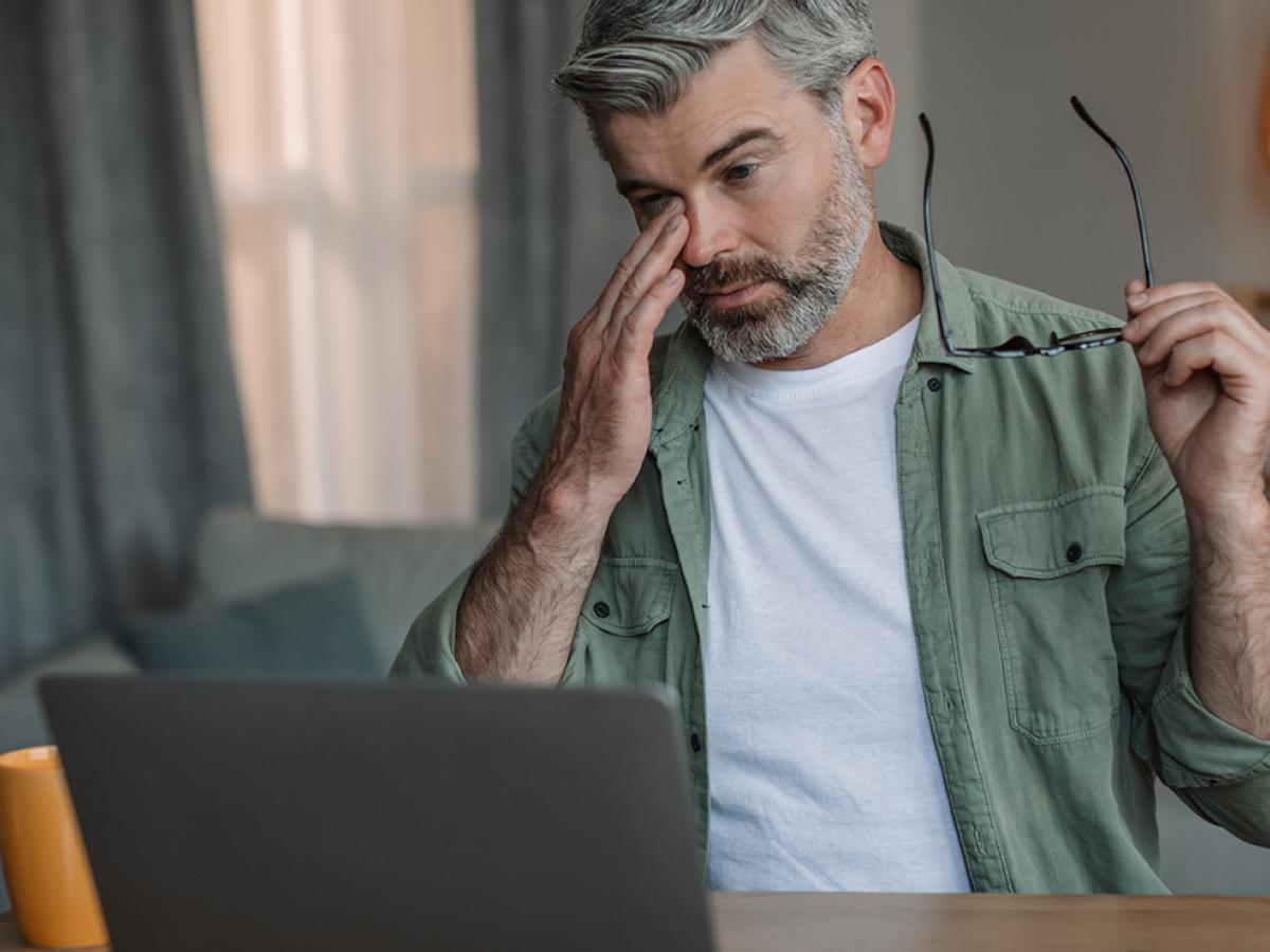 A man rubs his eyes after removing his glasses.