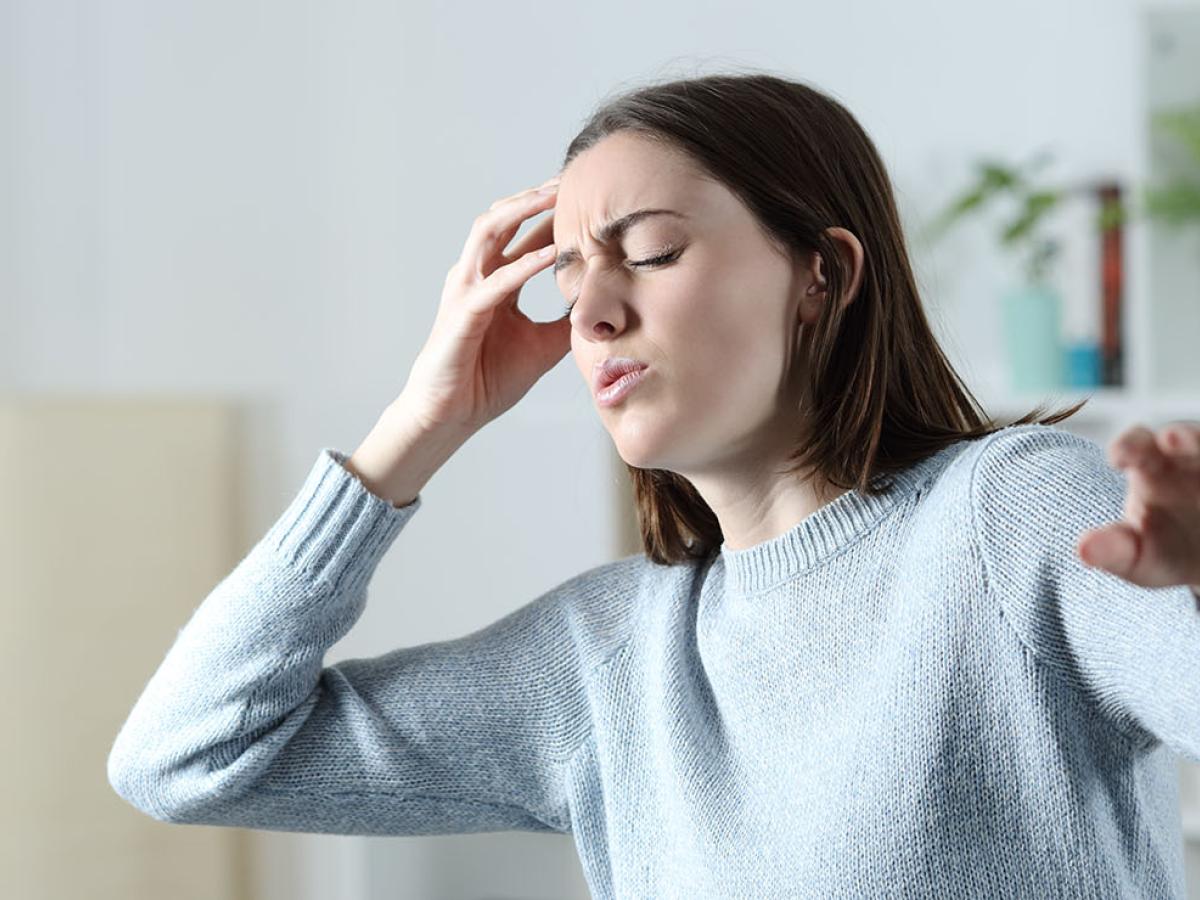 A woman holding her head, reaching out to prevent a fall.