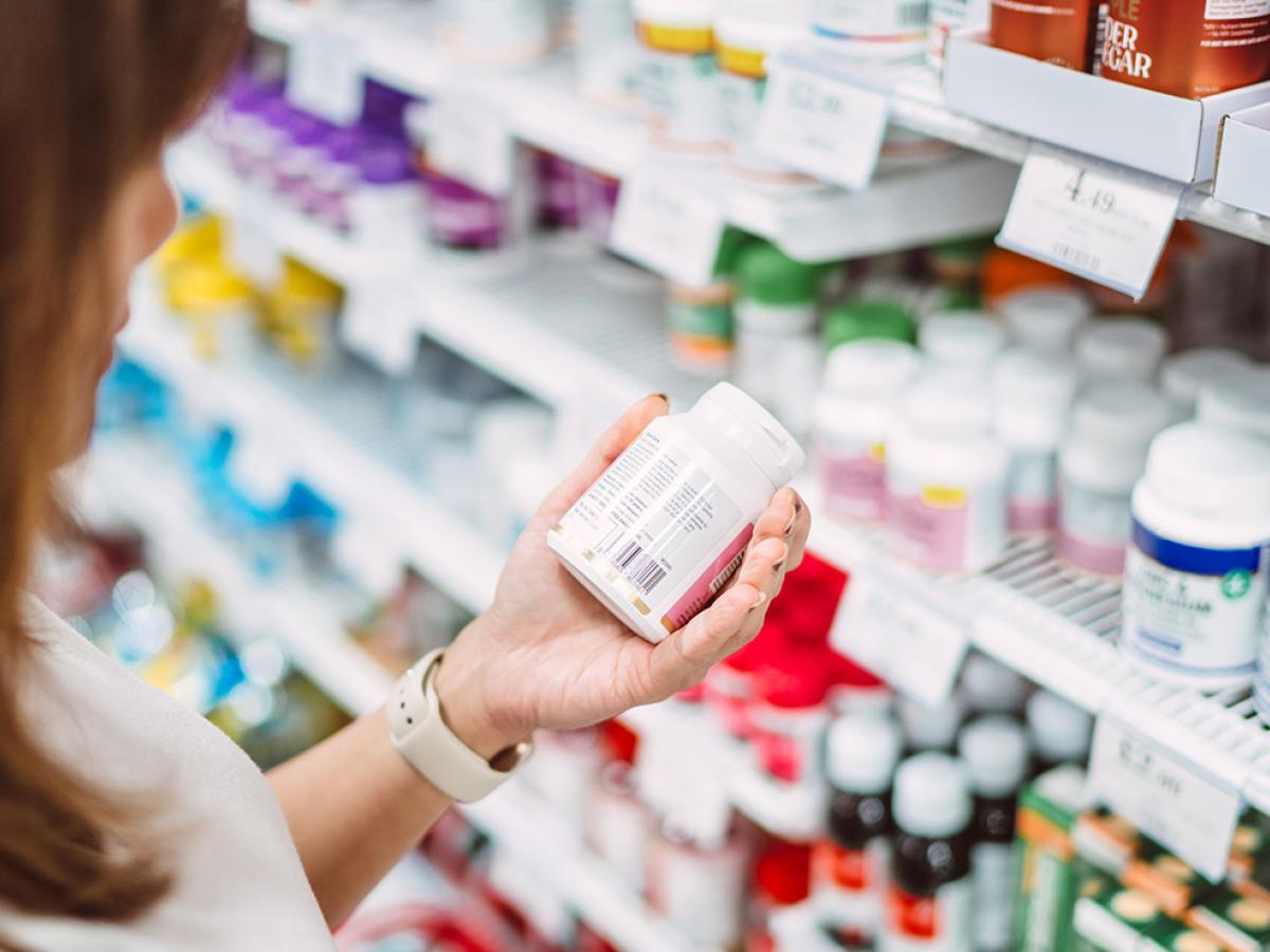 A woman is examining the label of some supplements.