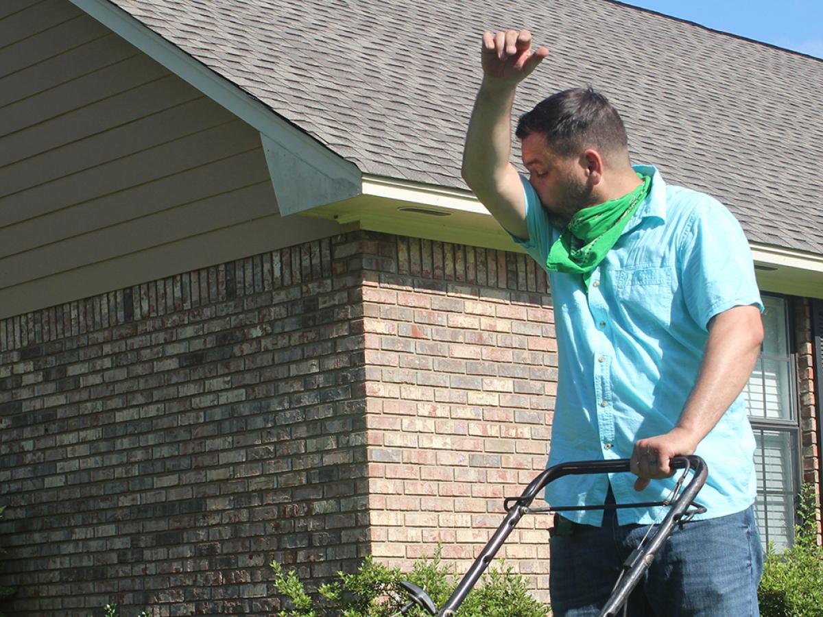 A man sneezing while mowing the lawn.