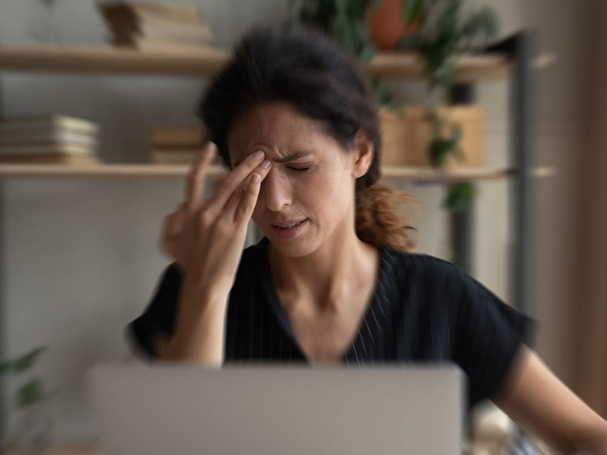 A woman applying pressure to her temple.