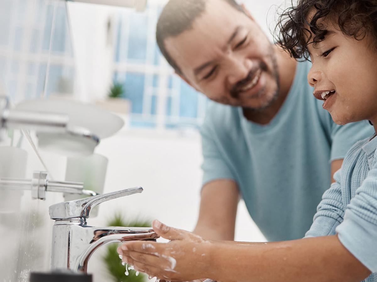 A father teaching his son how to wash his hands.