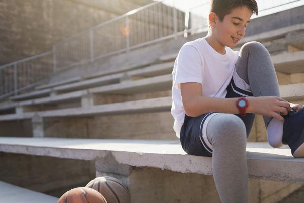 A teen tying his shoe, sitting on a stadium seat.