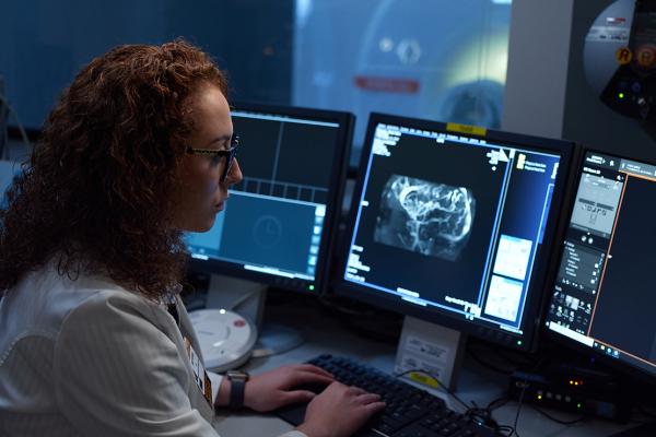 A medical professional looking at a scan on a computer.