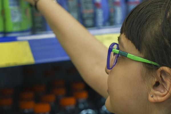 A child reaching for an energy drink at the grocery store.