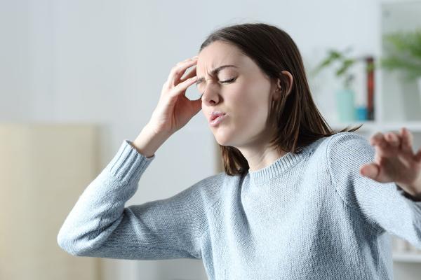 A woman holding her head, reaching out to prevent a fall.