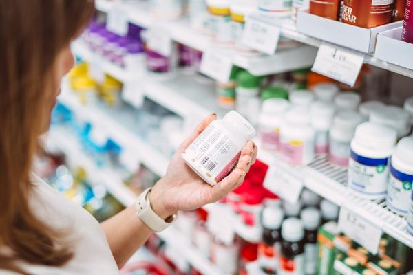 A woman is examining the label of some supplements.