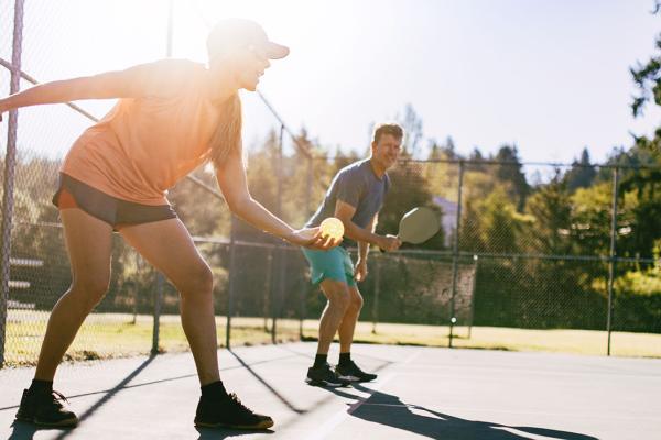 People outdoors playing pickleball. 