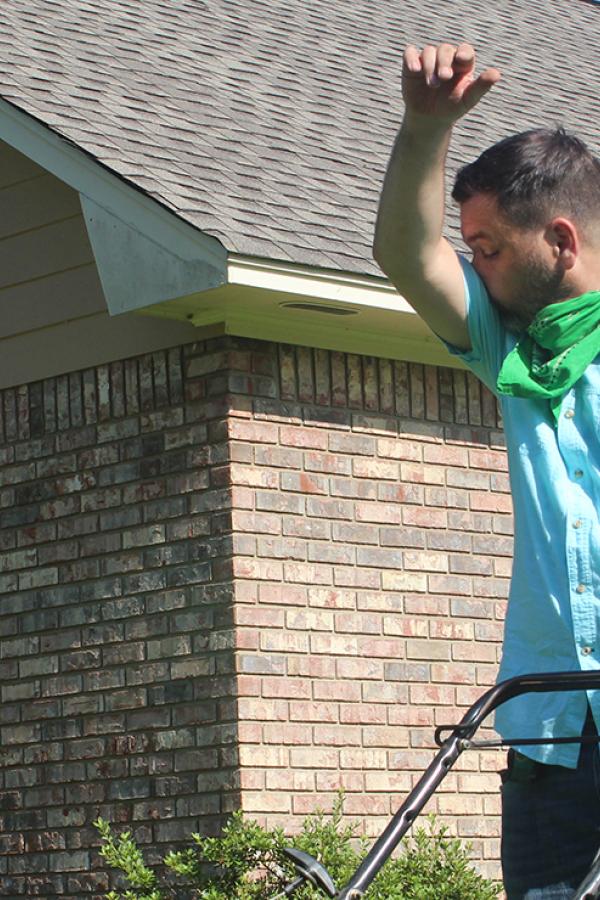 A man sneezing while mowing the lawn.