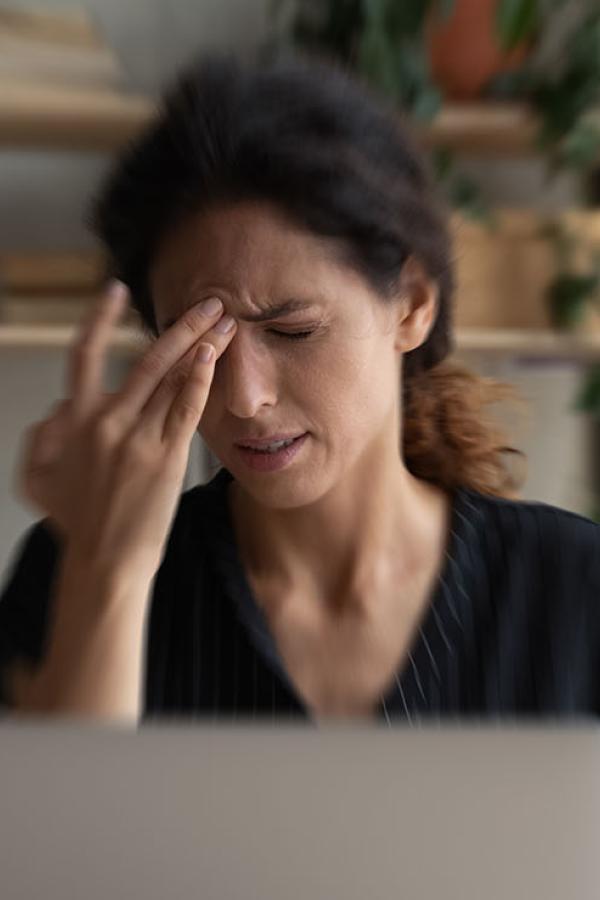 A woman applying pressure to her temple.