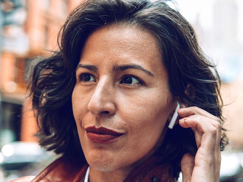 A woman outdoors wearing earbuds.