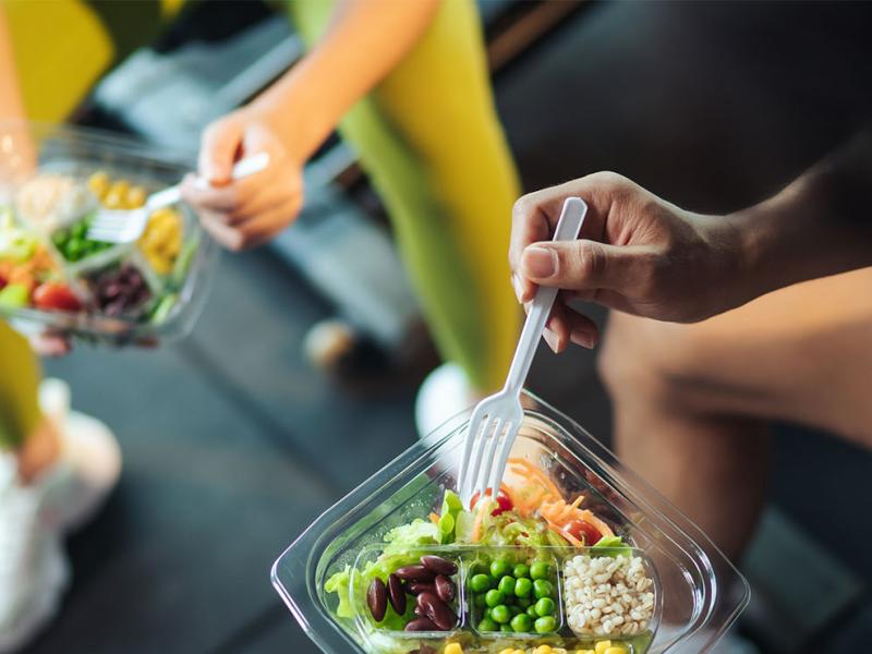 Two athletes sitting down eating a meal.