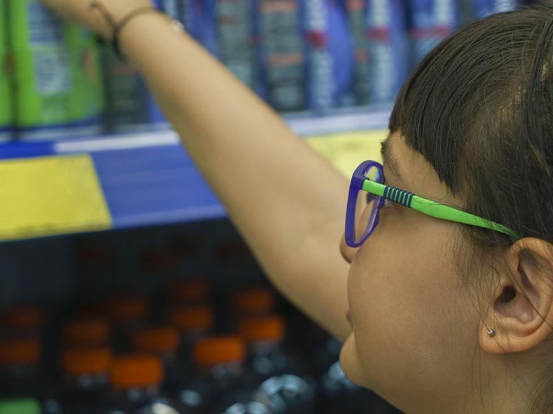 A child reaching for an energy drink at the grocery store.