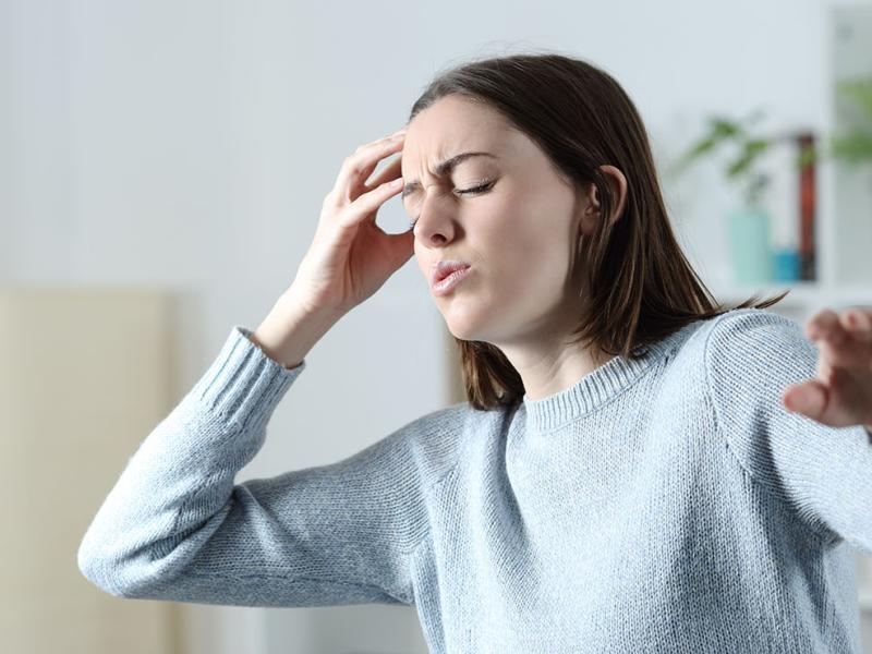 A woman holding her head, reaching out to prevent a fall.