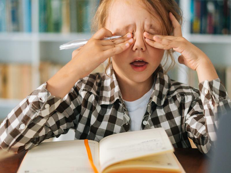 A little girl rubbing her eyes.