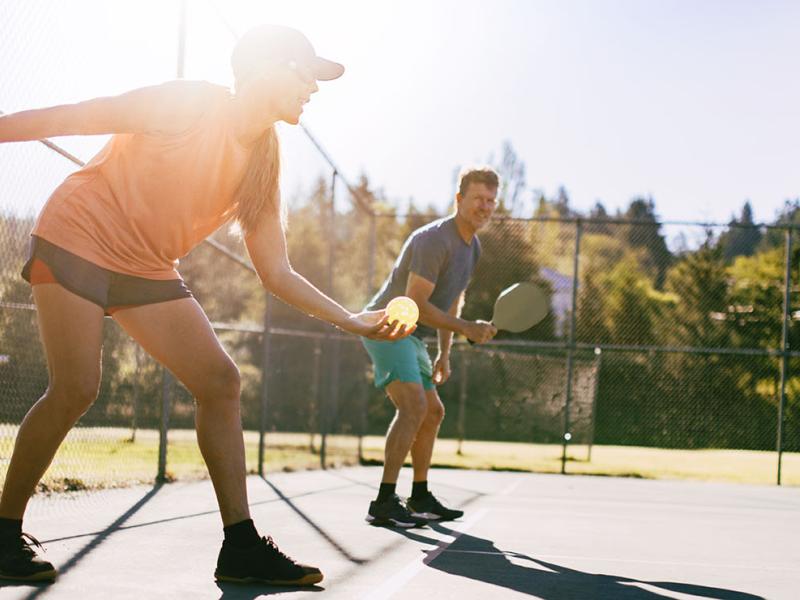 People outdoors playing pickleball. 