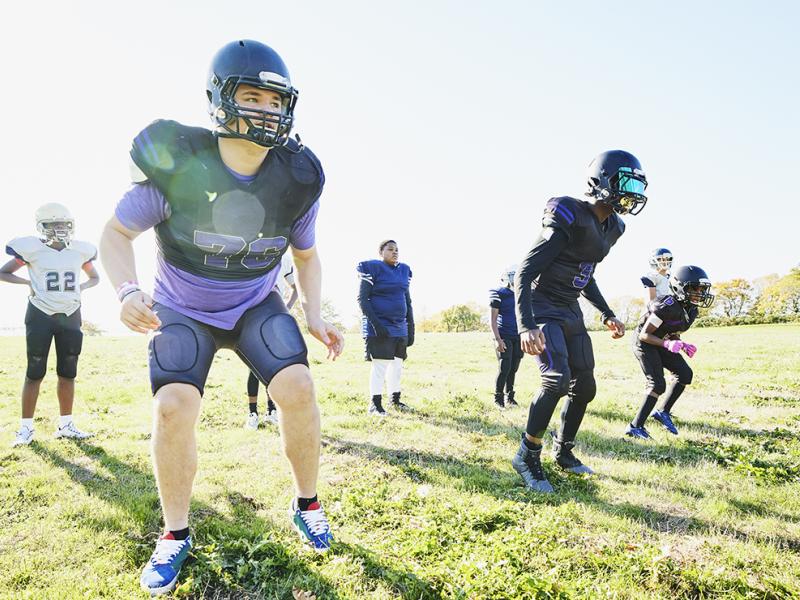 Students outdoors at football practice.